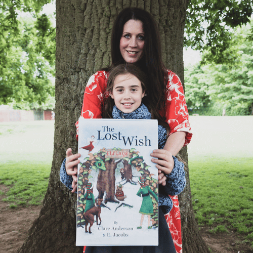 clare anderson and daughter siena holding the lost wish book stood in front of a tree