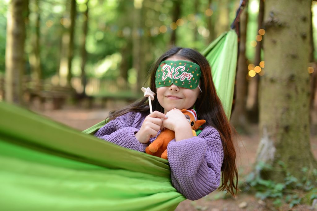 Young Girl with Elf Eyes Mask in Hammock with wooden wish wash and plush toy